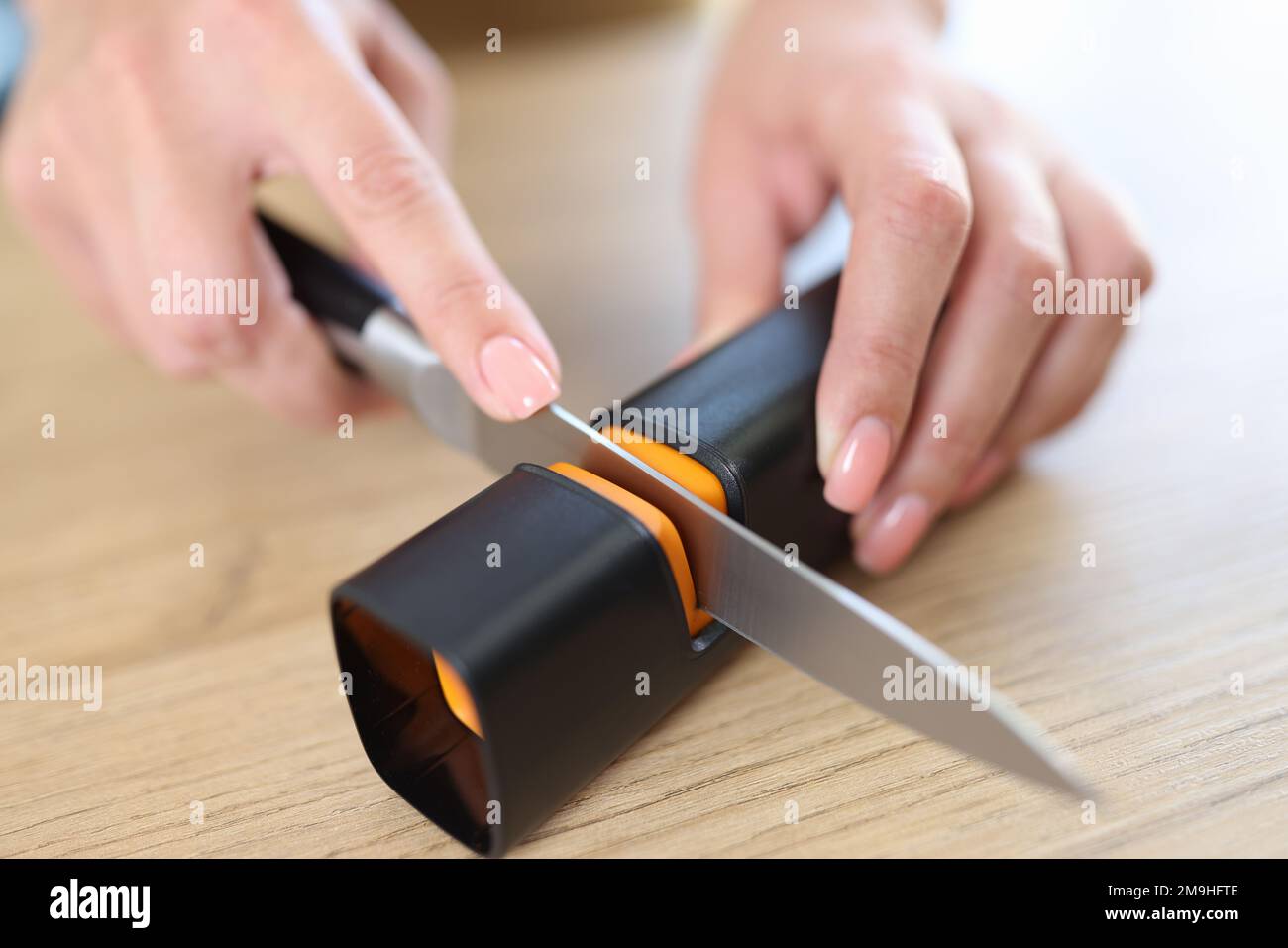 Premium Photo  Close-up strong male hands sharpen a kitchen metal knife  with a grindstone. home household knife sharpening.