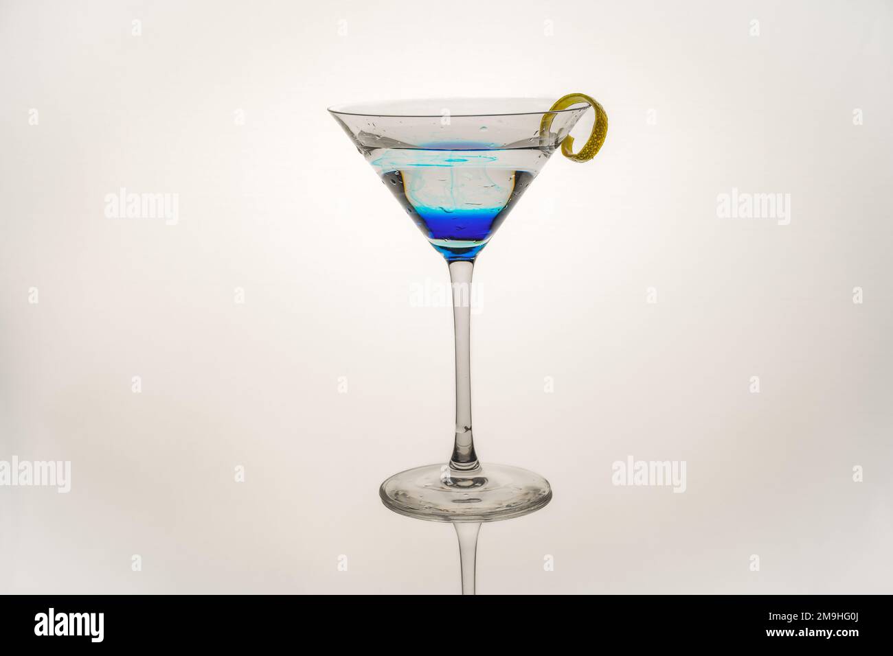 blue curacao infused vodka martini with lemon twist isolated on a white