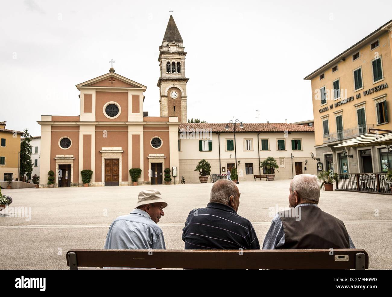 Men chatting in a town square in Tuscany Stock Photo