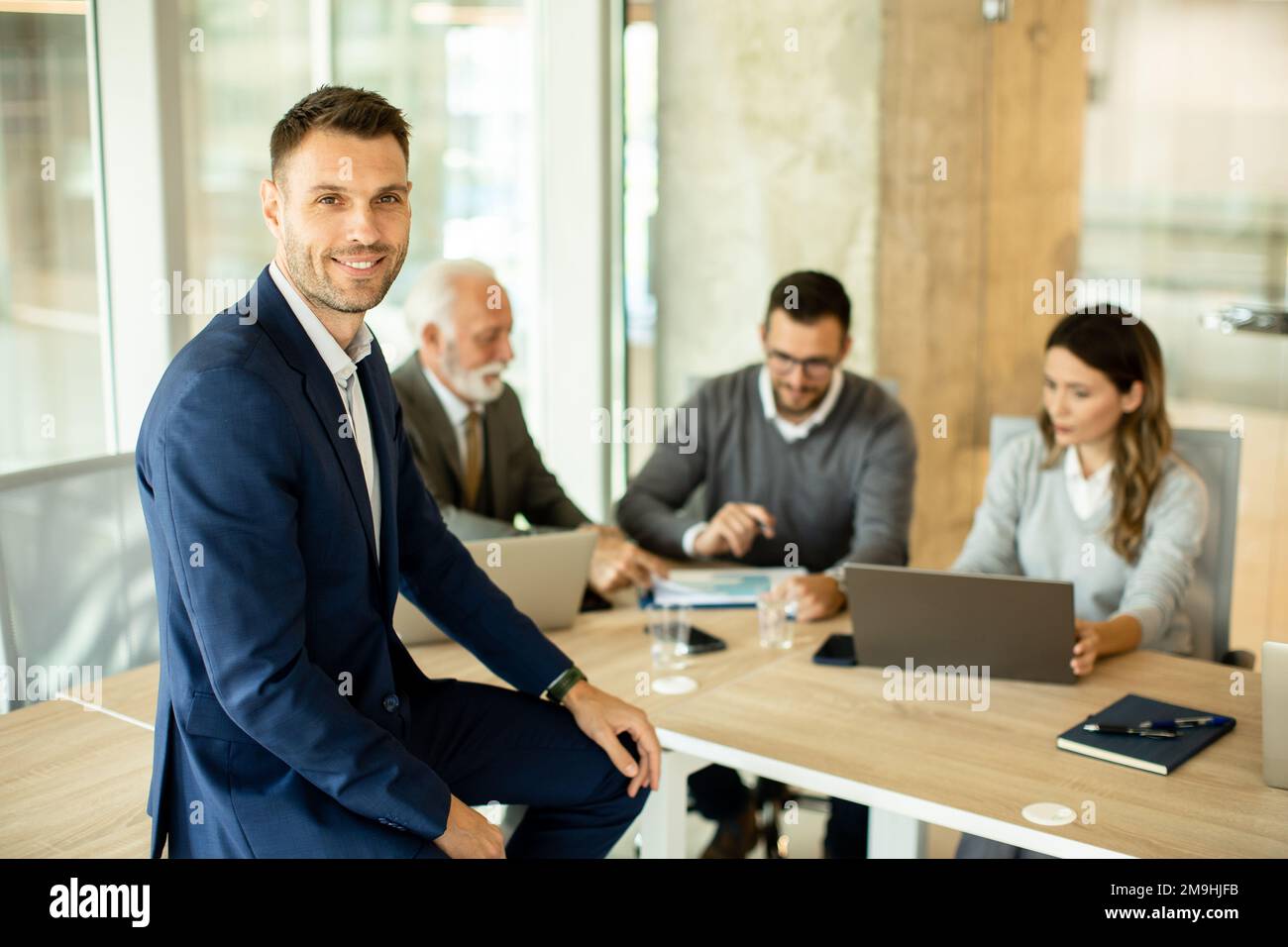 Handsome young businessman standing in front of his coleagues in the office Stock Photo