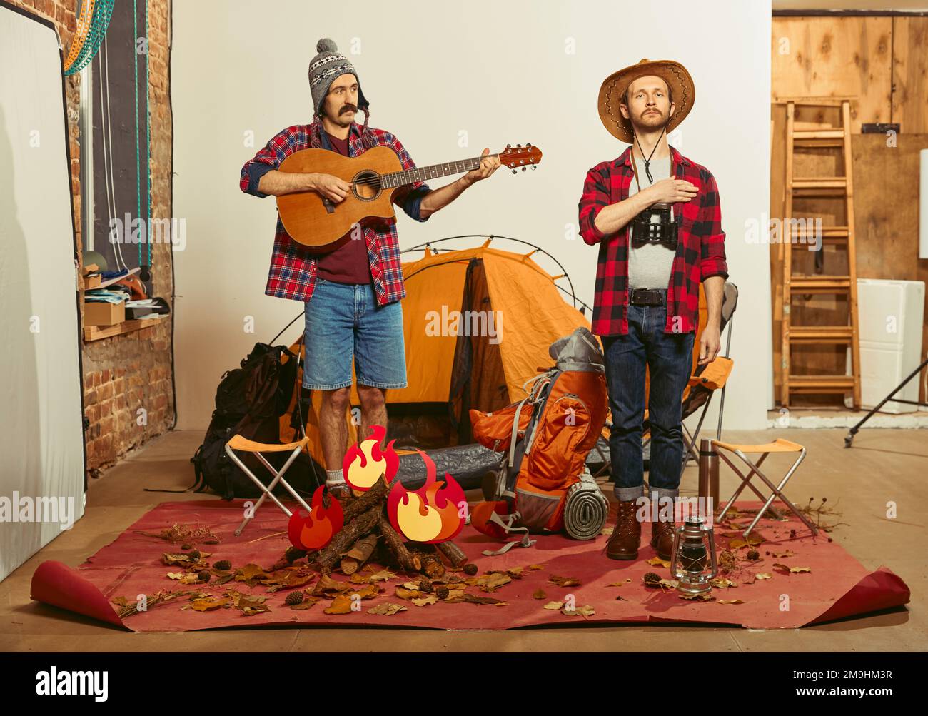 Singing anthem. Two men imagining, recreating camping activity indoors