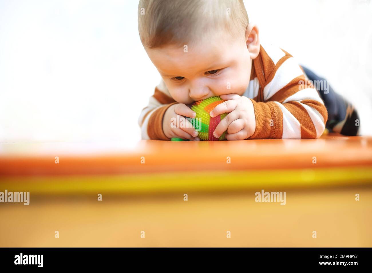 Baby plays with toys. Closeup view of cute baby boy lies on its