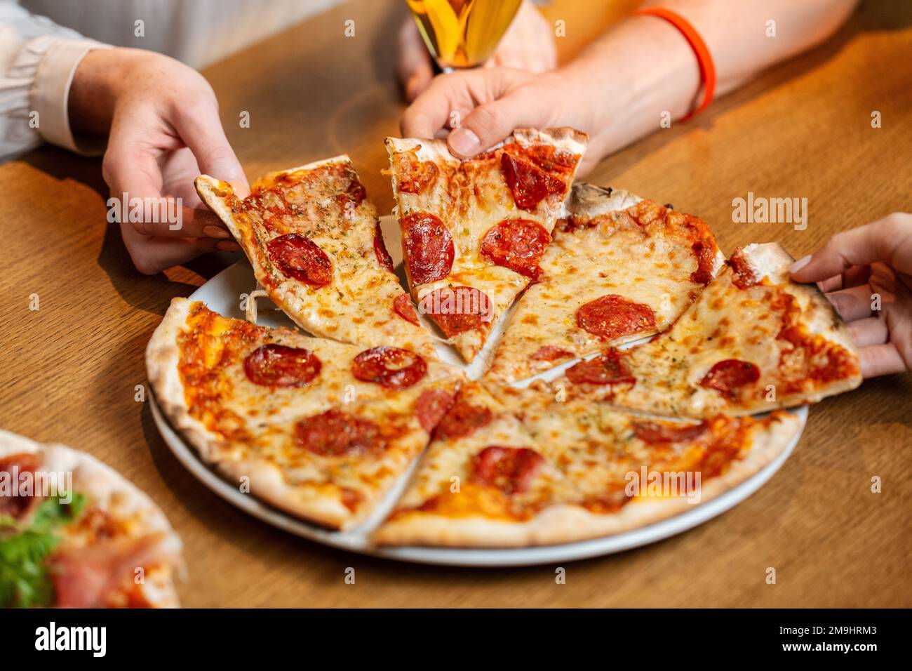 close up of friends eating pizza at restaurant Stock Photo