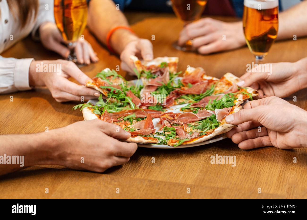 friends eating pizza with beer at restaurant Stock Photo