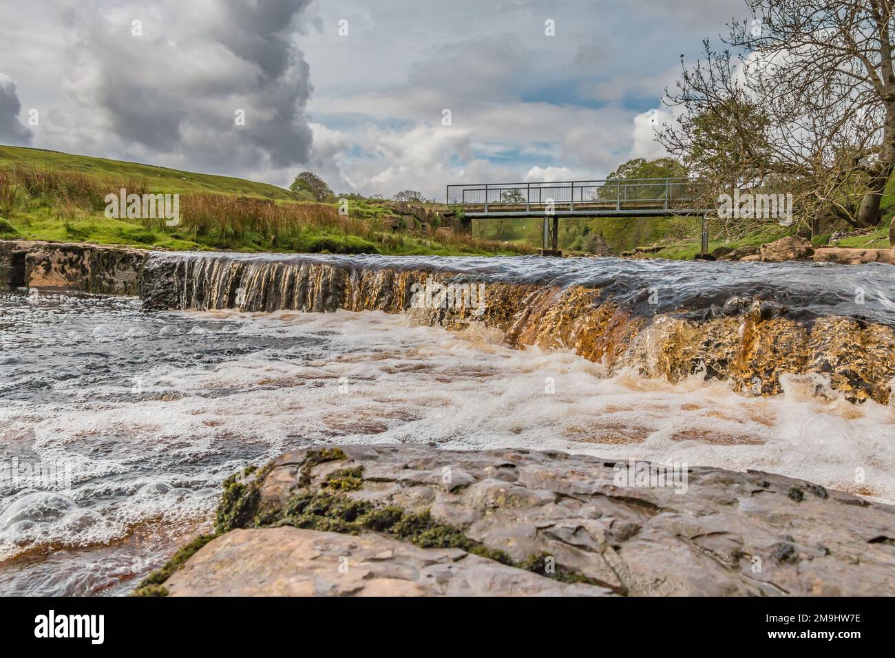 Cascade and footbridge over Sleightholme Beck, East Mellwaters, Bowes. The Pennine Way long distance footpath passes close by. Stock Photo