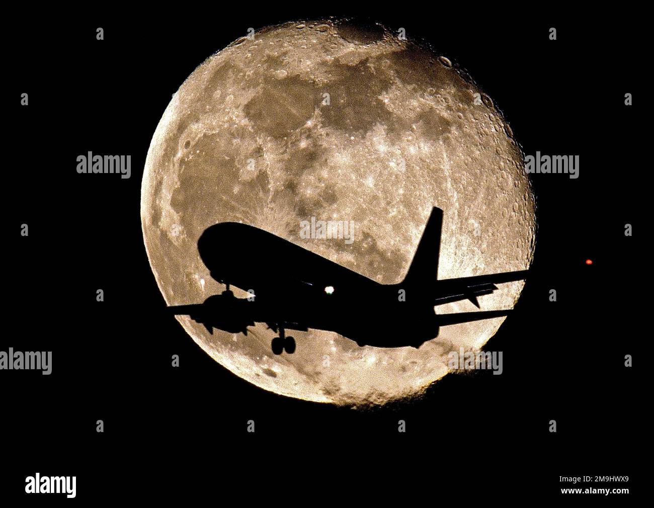 Jet in silhouette in front of the Moon Stock Photo