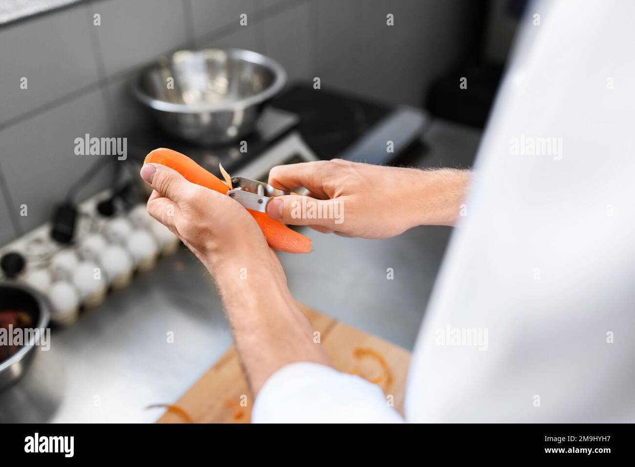 close up of chef with peeling carrot on kitchen Stock Photo