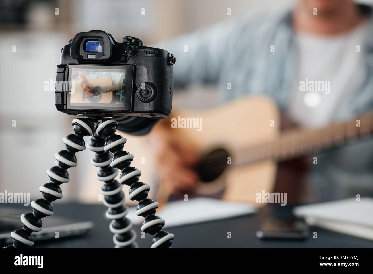 camera recording video of man playing guitar Stock Photo