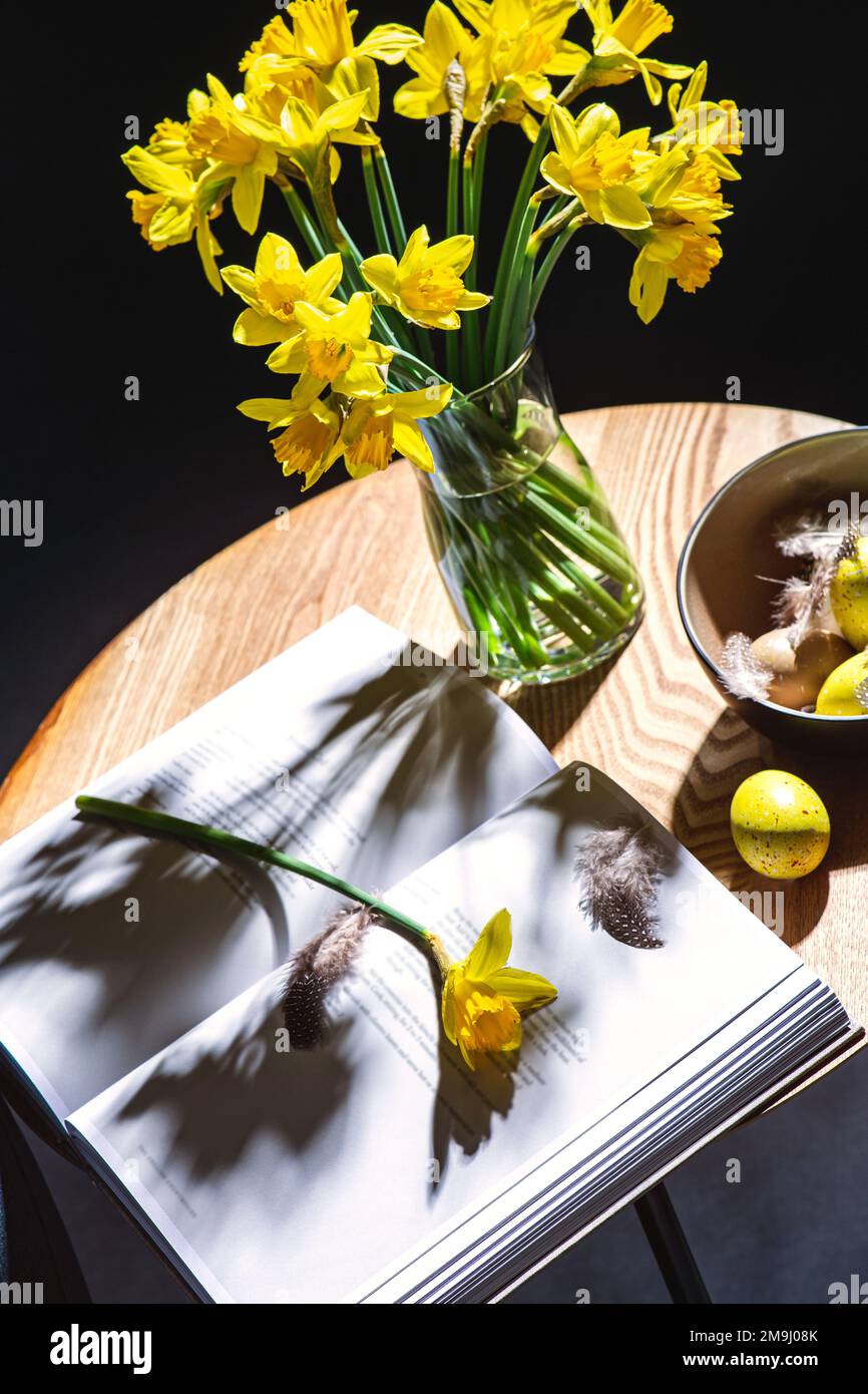 easter eggs, daffodils and magazine on table Stock Photo