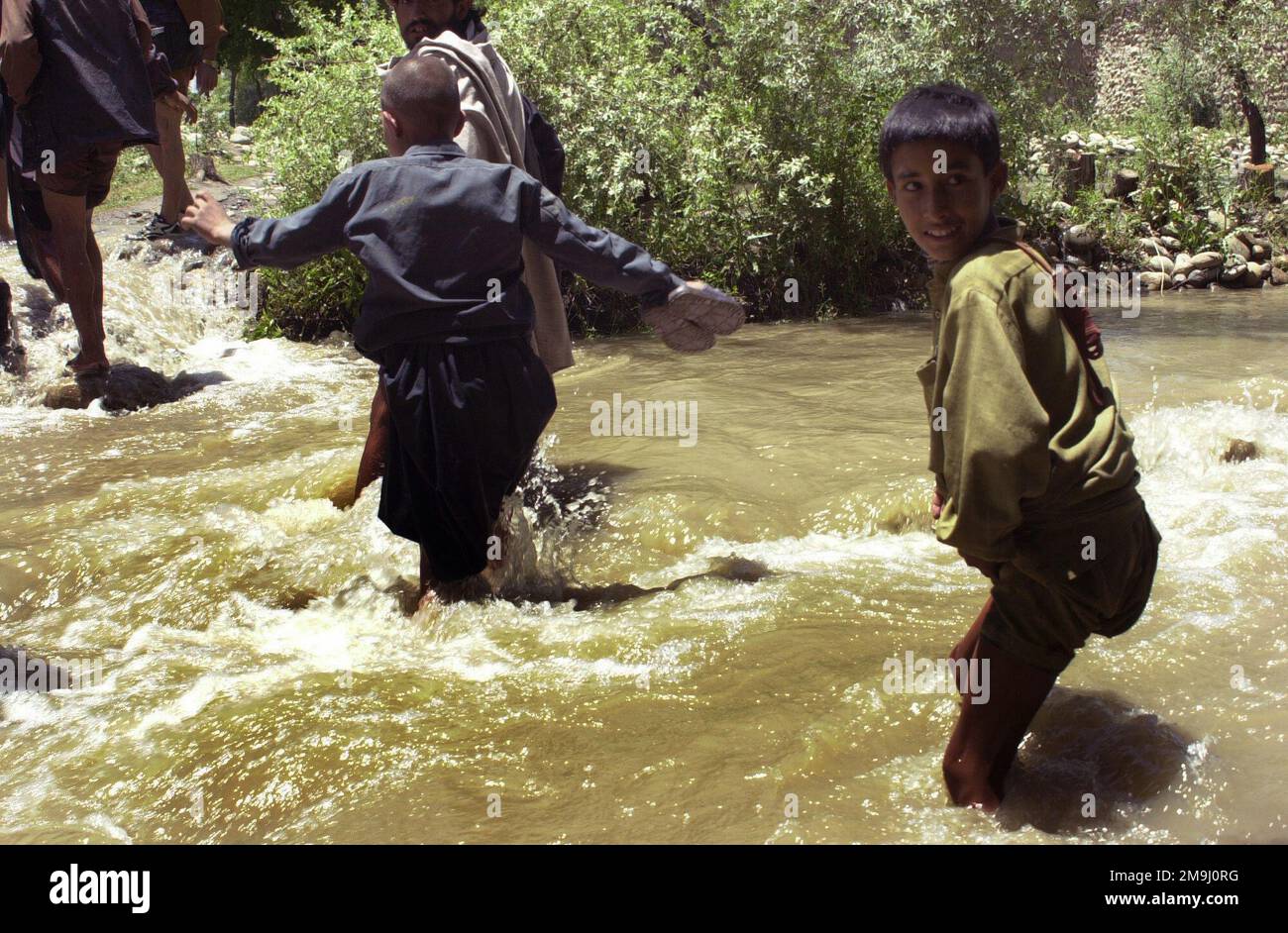 Local Afghanistan civilians cross a flooded stream near the town of ...