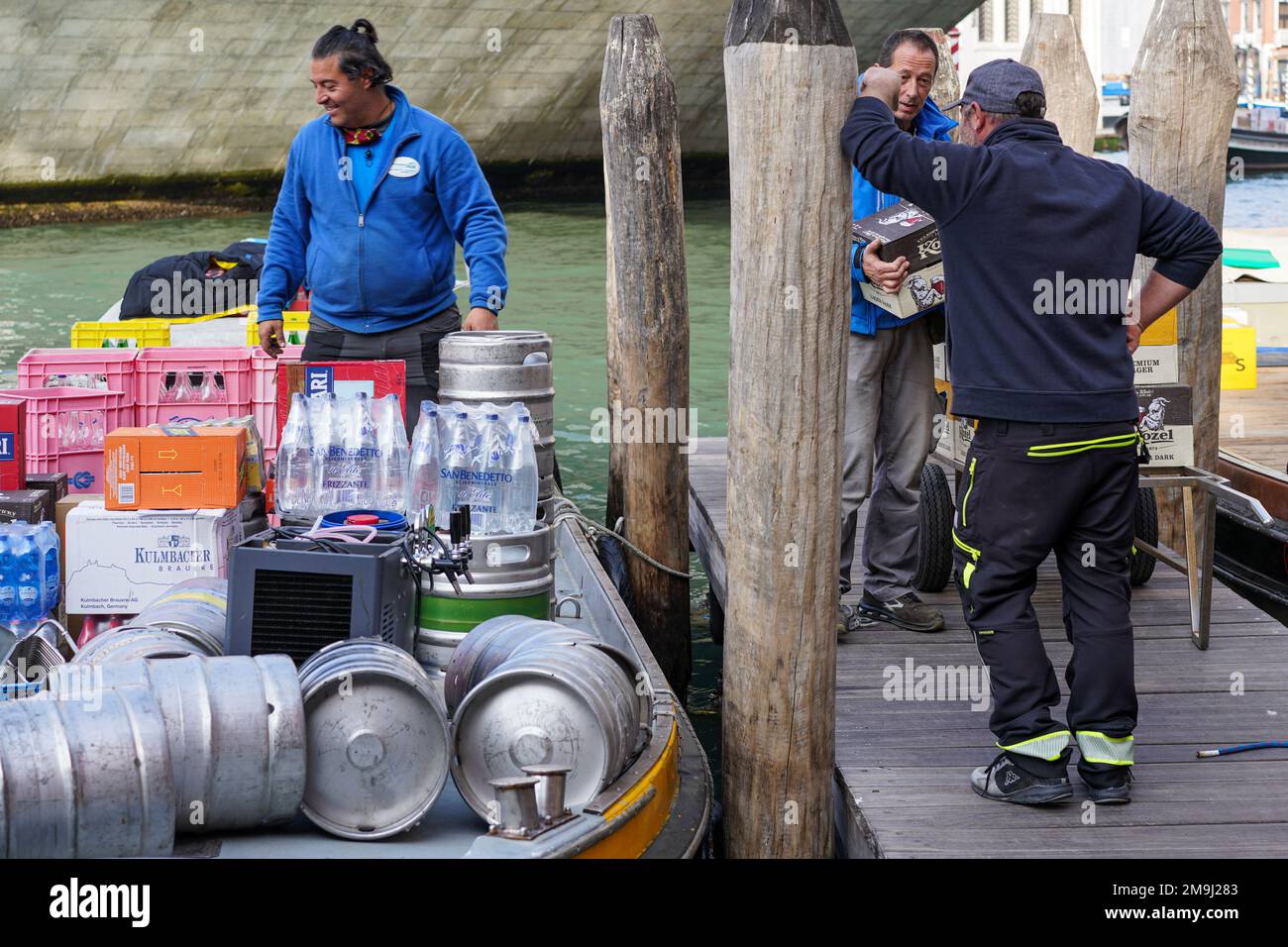 A beverage wholesaler uses his boat to deliver barrels and bottled drinks to a local trader on a canal in Venice. Stock Photo