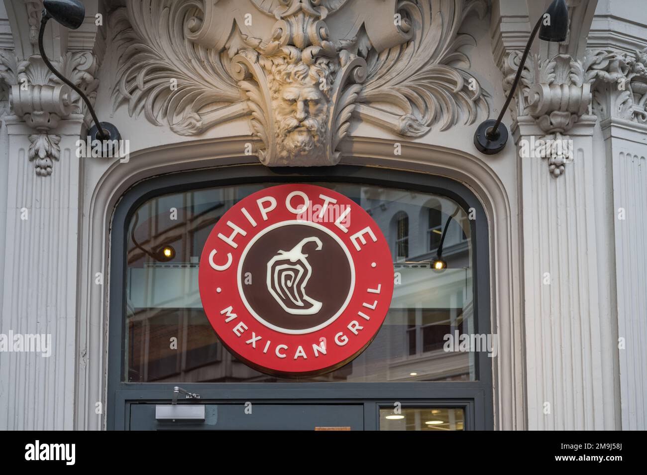 Stone carving and logo sign above entrance door to Chipotle Mexican