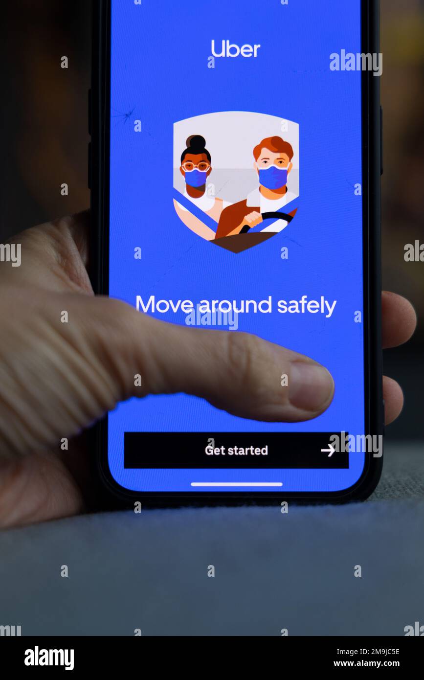 Hand holding a smartphone with Uber icon on screen. Move around safely ...
