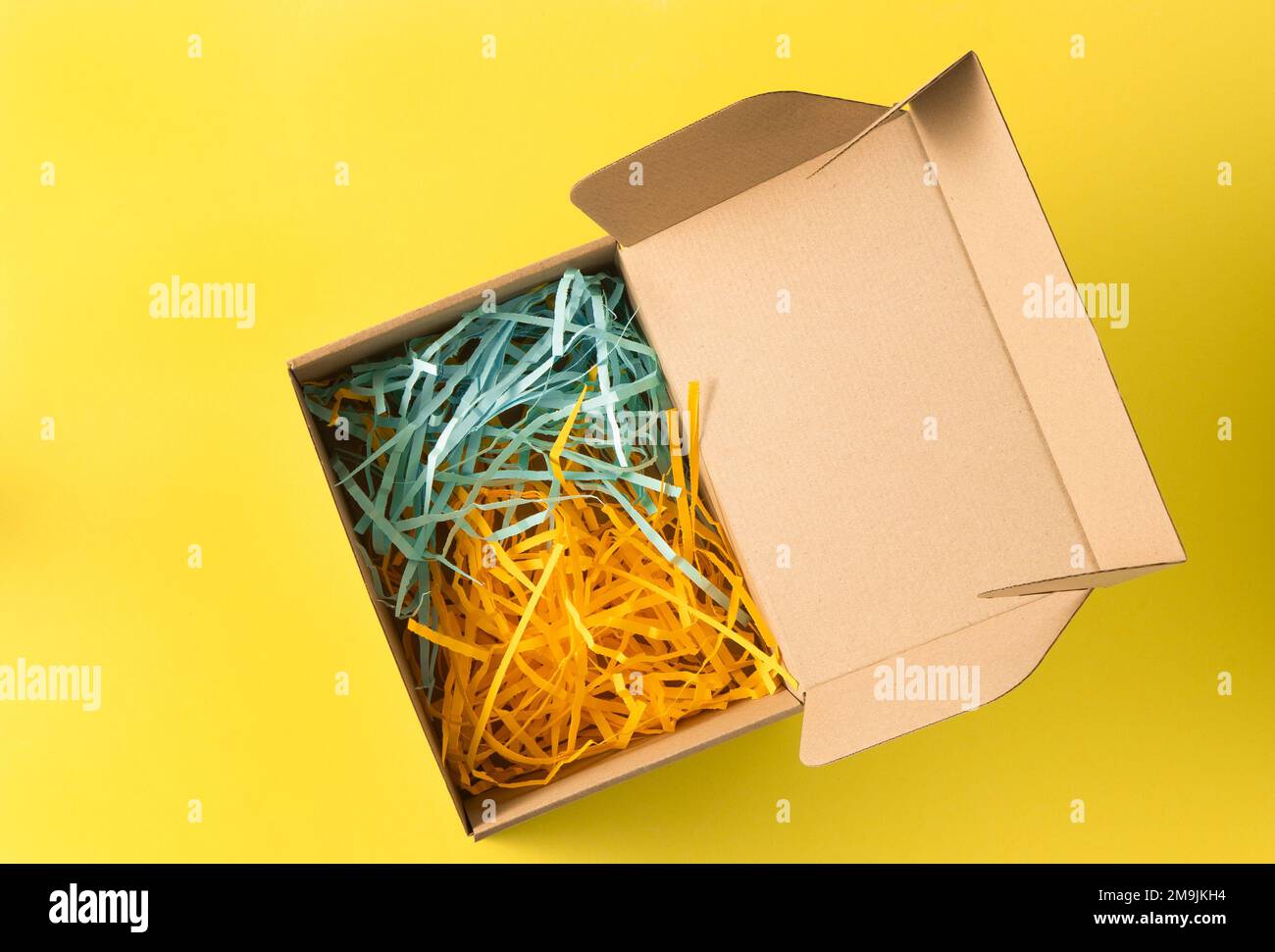 Gift wrap. Box with yellow and blue paper filling. Top view from above