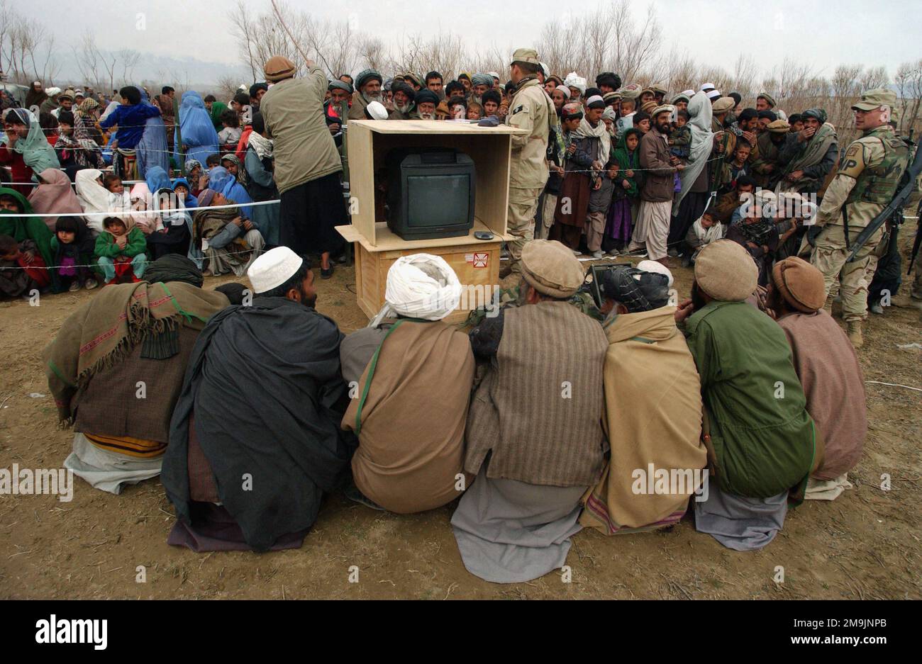 030121-F-7203T-022. [Complete] Scene Caption: A group of local Afghani men from the village of Aroki, located in the Kapisa Province of Afghanistan, prepare to watch a video entitled 'Why We Are Here' which explains the US Military involvement in the war on terrorism during a Medical Civil Action Program (MEDCAP) held in their village. US Army (USA) Soldiers from the 48th Combat Support Hospital, along side US Air Force (USAF) Airmen from the 455th Air Expeditionary Wing (EAW) and Republic of Korea (ROK) Army Soldiers from the 924th Medical hospital, operate the programs, which provides free m Stock Photo