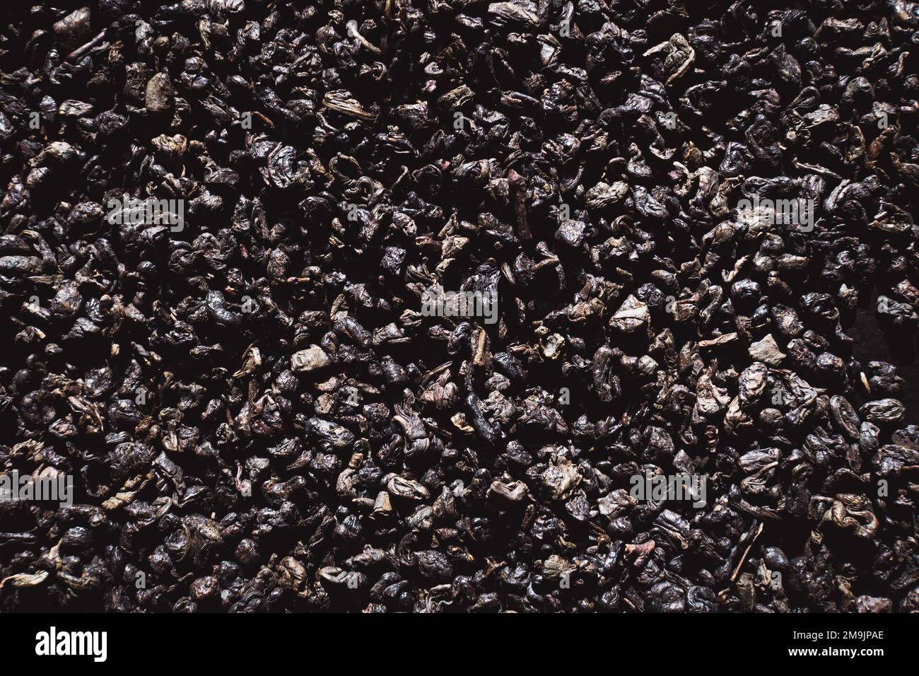 Black tea texture background. Black dried tea leaves, marco. Pattern of black tea leaves on a flat surface. Stock Photo