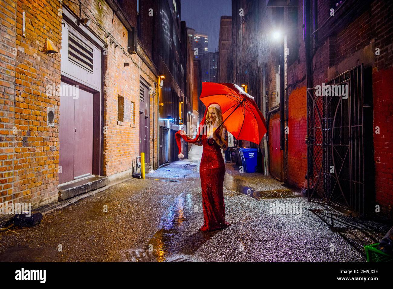 Woman with red dress, Santa hat and umbrella in alley, Seattle, Washington, USA Stock Photo