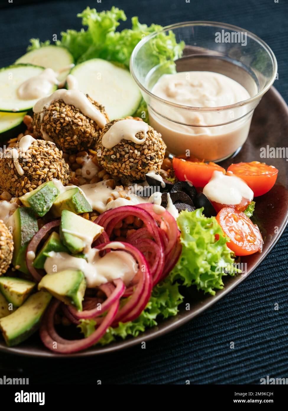 Healthy mixed salad as dinner with home made falafel balls and a tahini dressing. Stock Photo