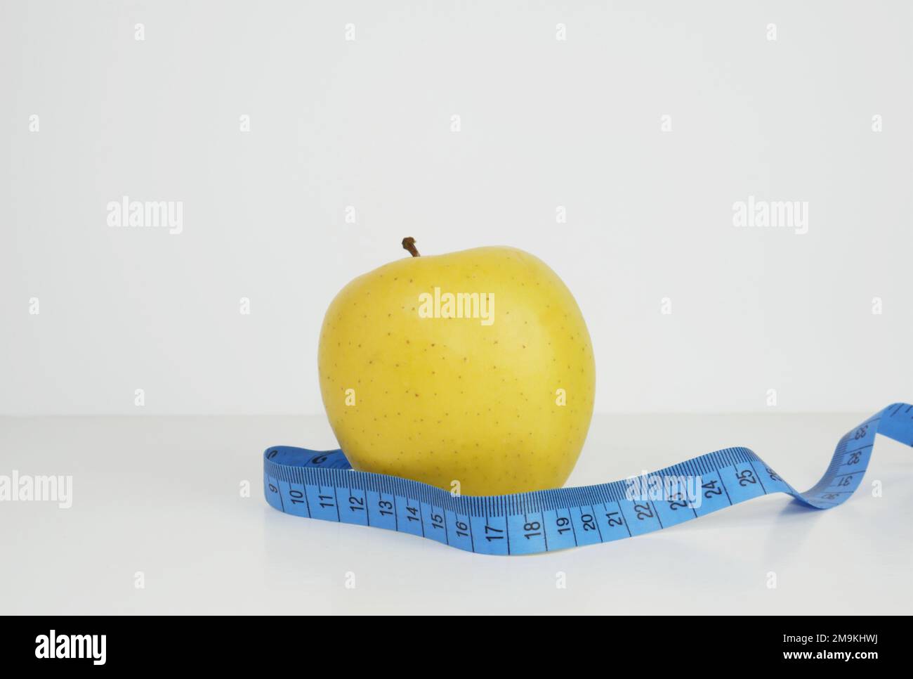 A single yellow apple and blue ruler on the white background Stock ...