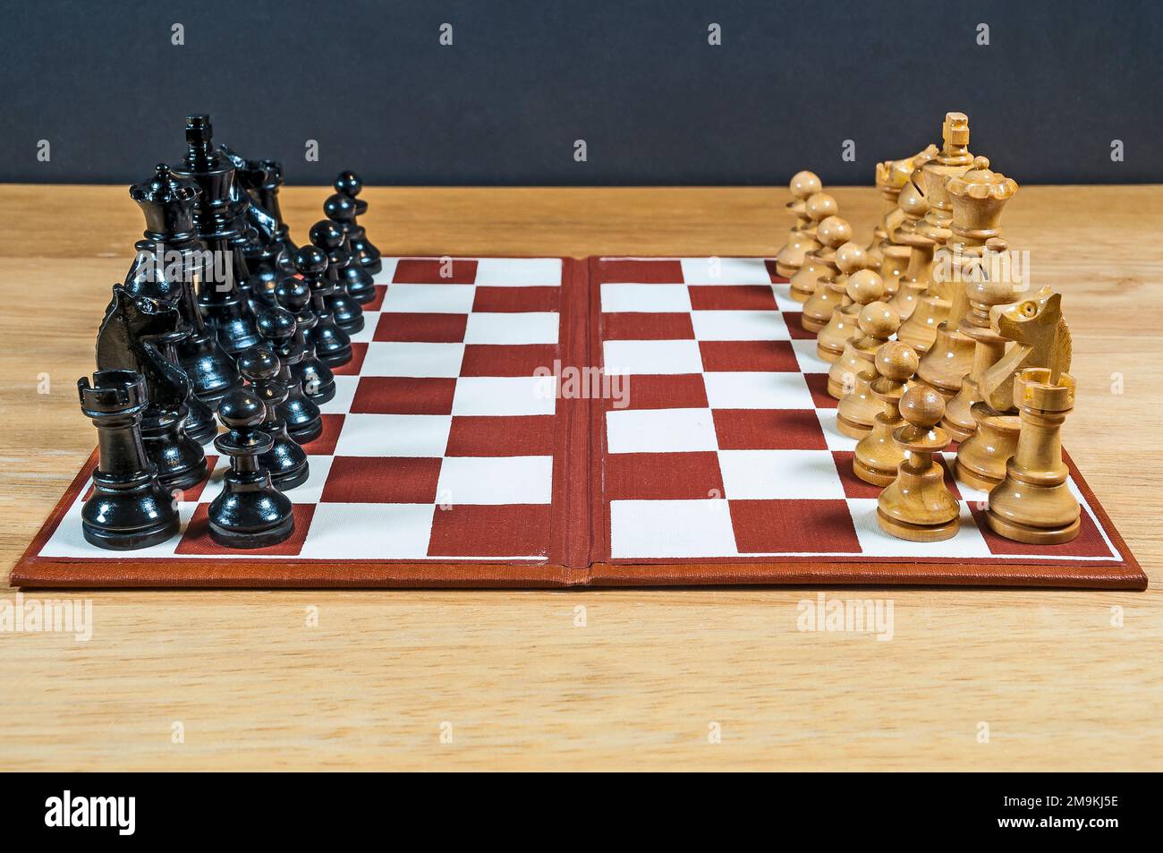 Small Chess Set and Chessboard as shown down middle of board with dark pieces on one side and light pieces on the other. Stock Photo