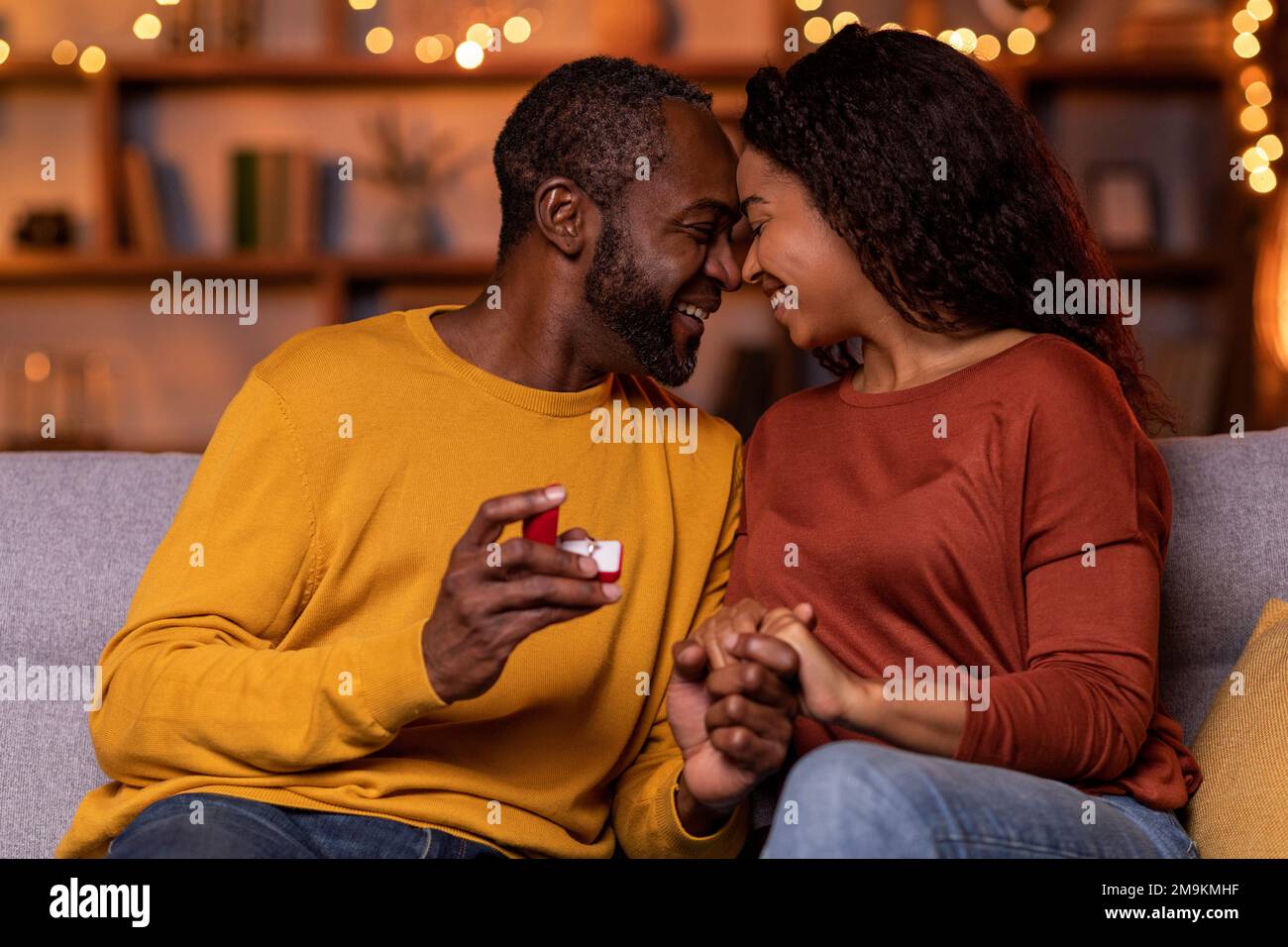 Emotional african american man holding girlfriend hand and ring Stock Photo