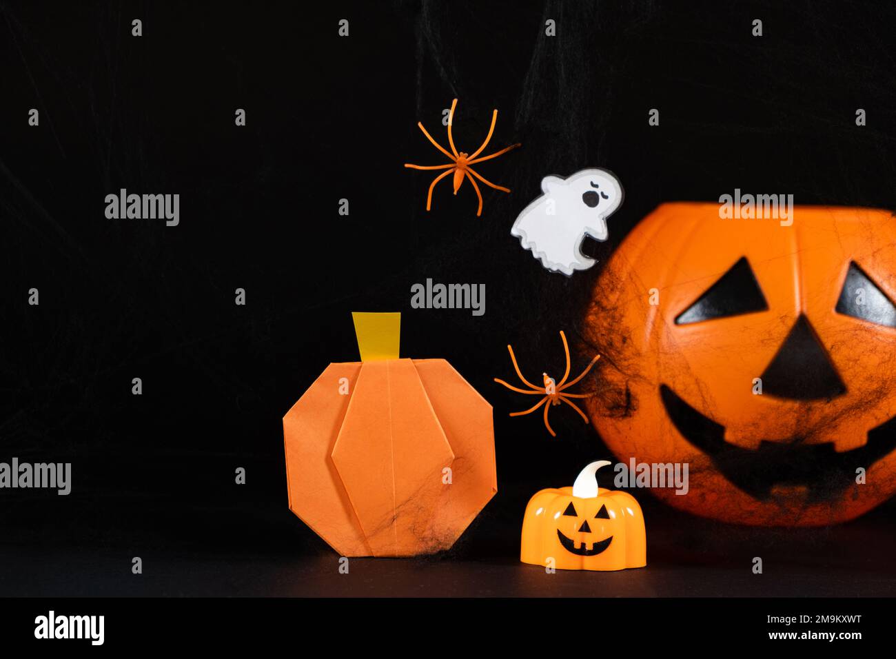 Orange pumpkins, a ghost, spiders and spider webs on a black background ...