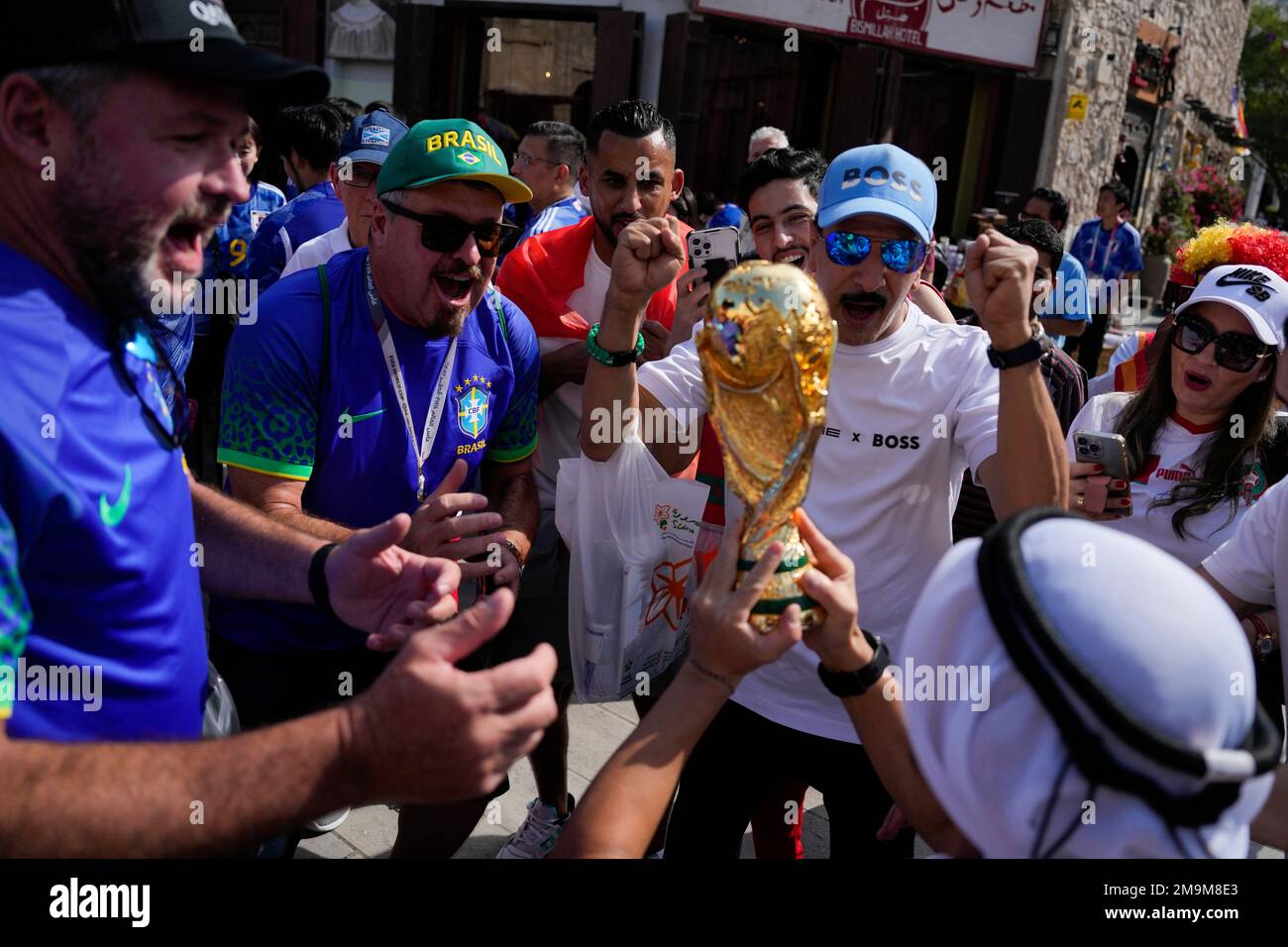 Soccer fans cheer as a man hoists a replica of the World Cup trophy at