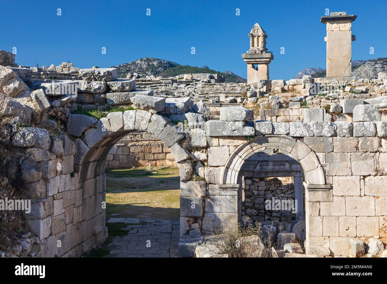 Entrance gate to theatre of Xanthos ancient city - part of Lycian way. Tomb monument of king Kybernis ( Harpy Tomb), Pillar Tomb on background. Stock Photo