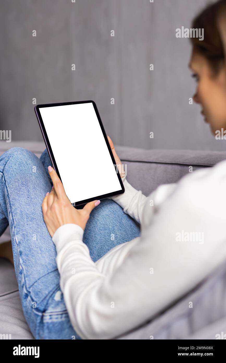 Young woman with tablet sitting on couch at home Stock Photo - Alamy