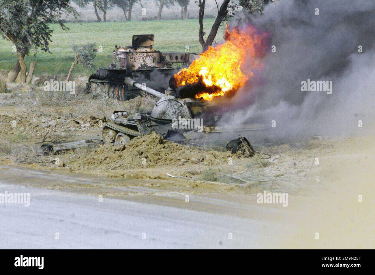 The burning remains of an T-55 Medium Battle Tank (MBT) near the An Nu'maniyah Bridge along Highway 27 during Operation IRAQI FREEDOM. IRAQI FREEDOM is the multinational coalition effort to liberate the Iraqi people, eliminate Iraq's weapons of mass destruction and end the regime of Saddam Hussein. Country: Iraq (IRQ) Stock Photo