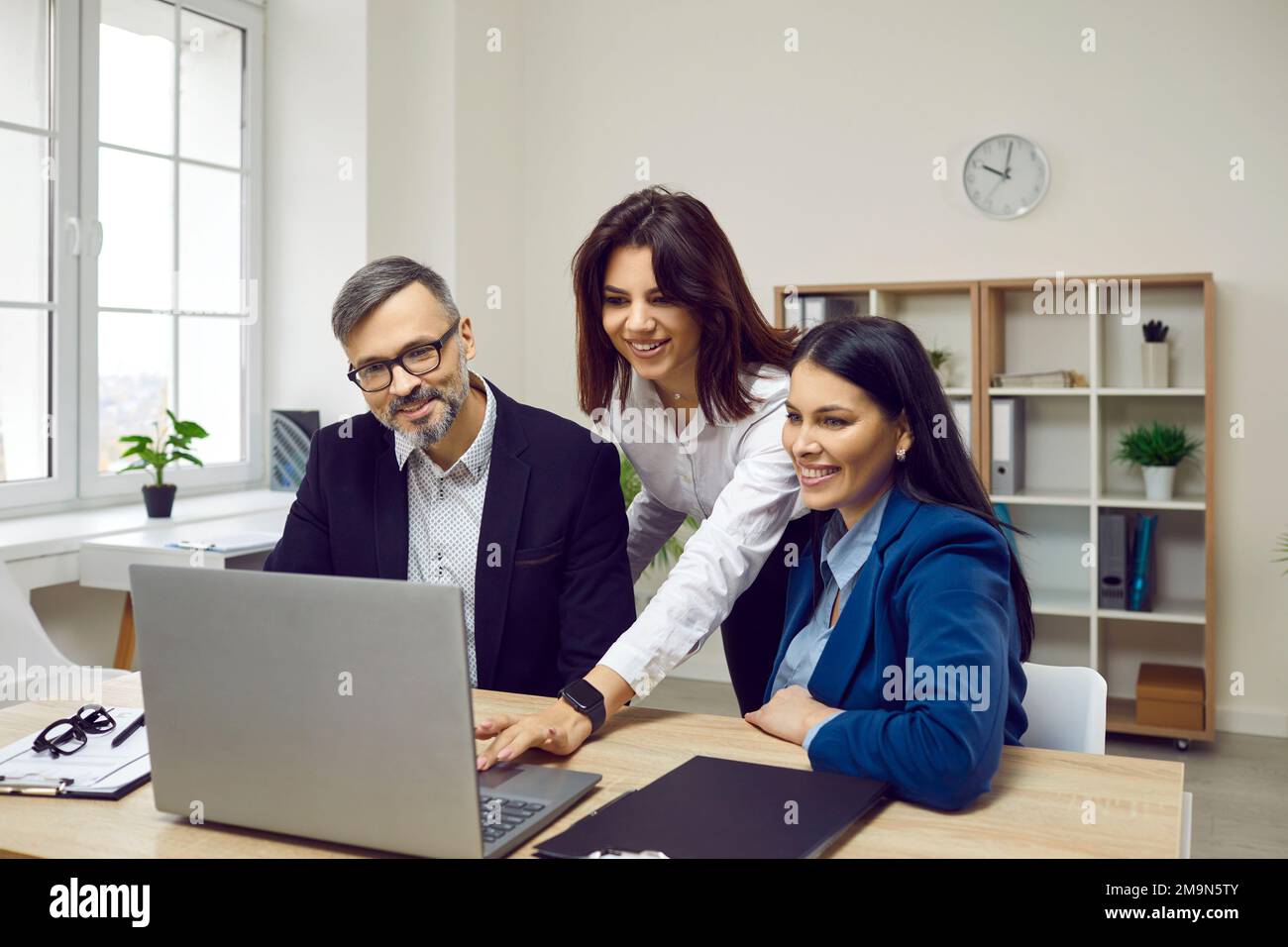 Group of confident business people analyzing data using laptop Stock Photo