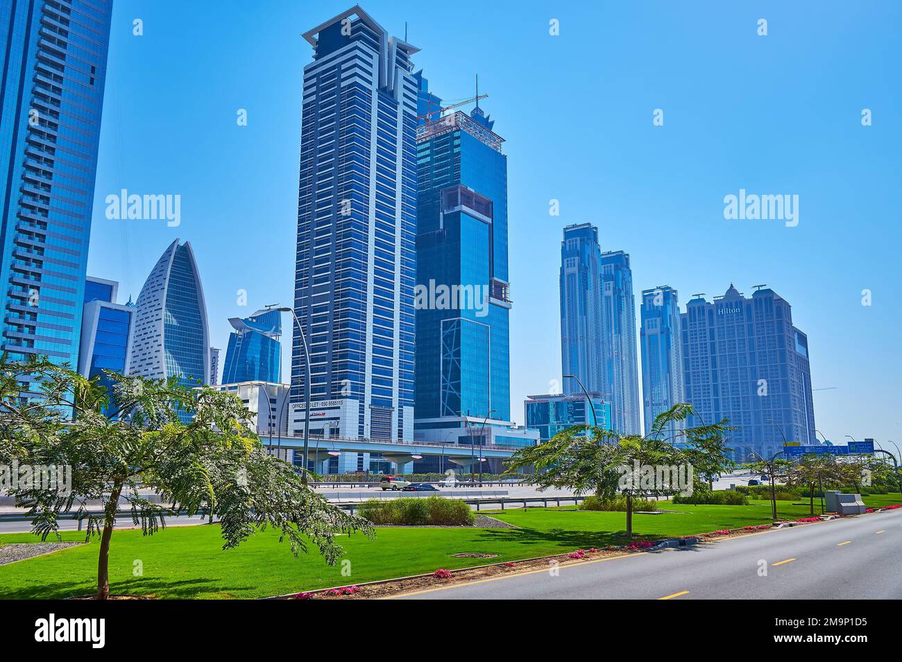 DUBAI, UAE - MARCH 6, 2020: Business Bay district with modern towers, Sheikh Zayed Road and lush green garden beds, on March 6 in Dubai Stock Photo