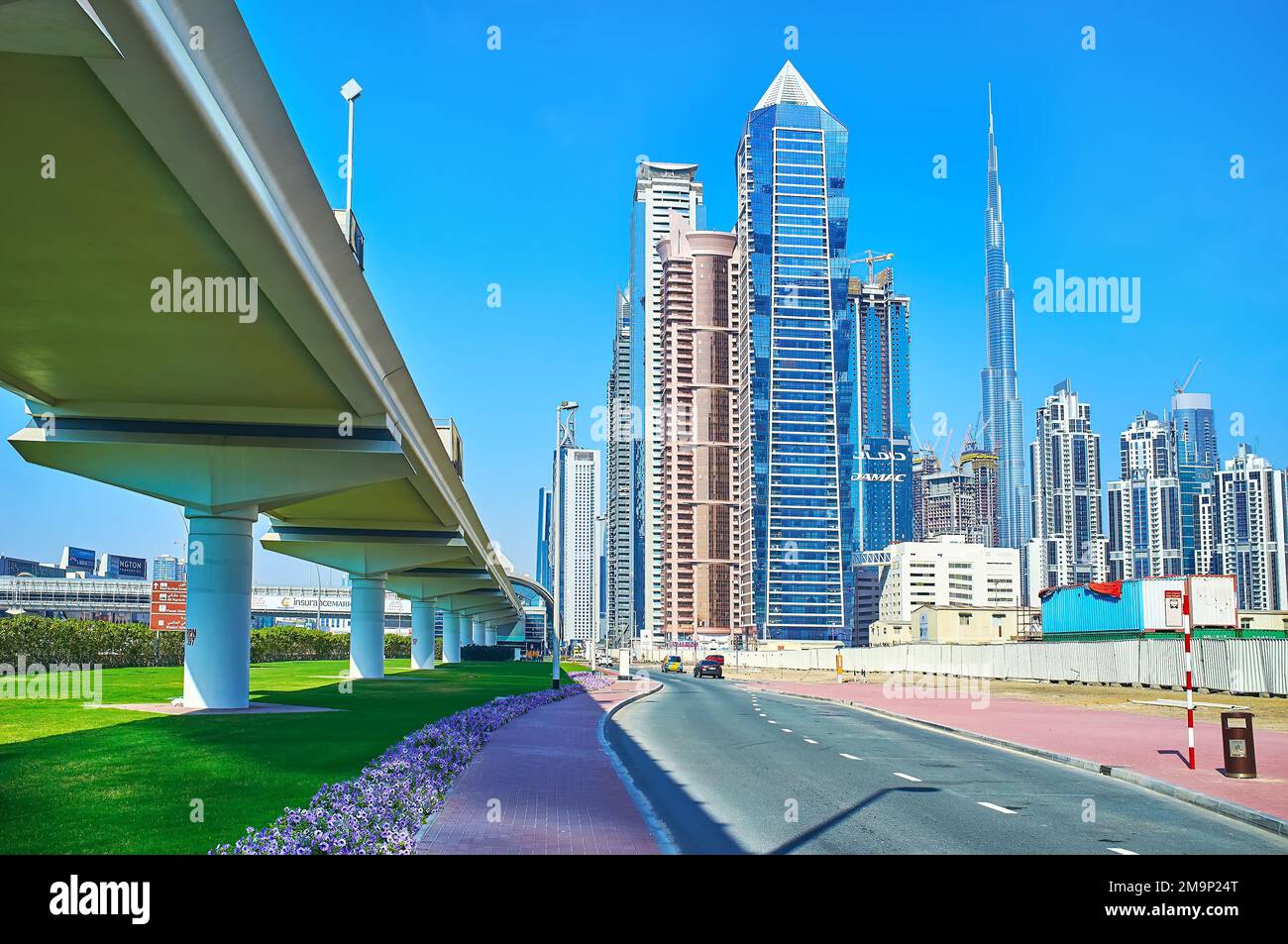 DUBAI, UAE - MARCH 6, 2020: Dubai Metro overpass and futuristic towers of Business Bay and Downtown against the bright blue sky, on March 6 in Dubai Stock Photo