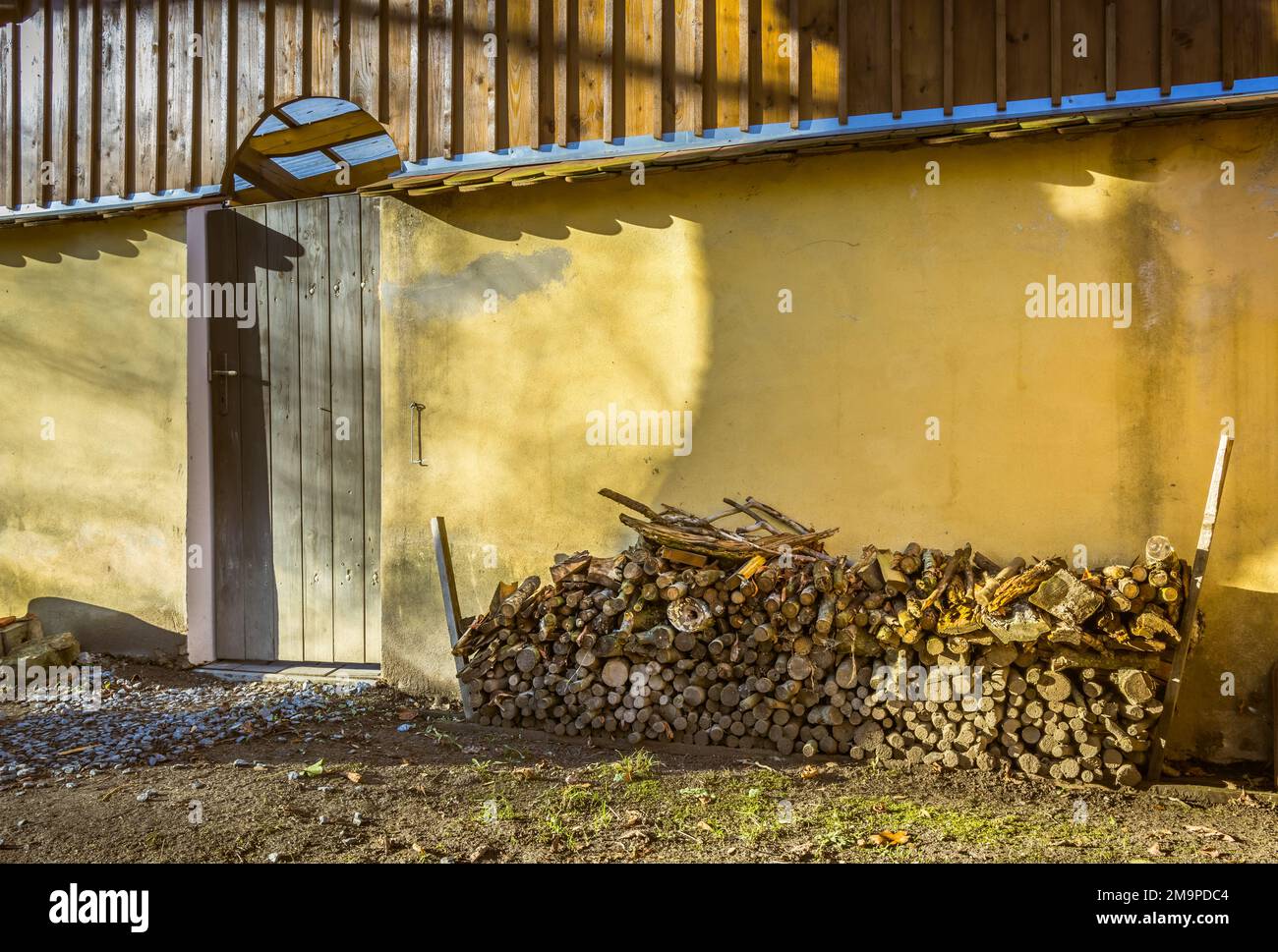 A pile of stacked firewood, prepared for heating the house, harvested for heating in winter on the house wall Stock Photo