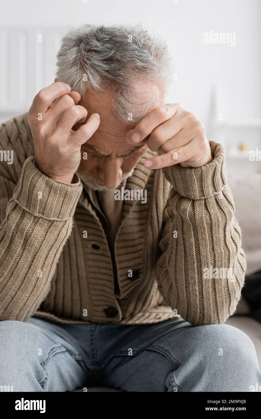 aged man with parkinsonian syndrome and trembling hands sitting with