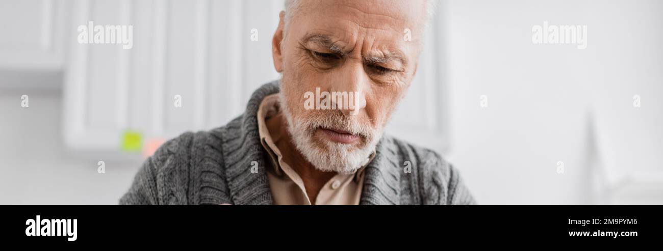 depressed grey haired man with alzheimer syndrome looking down at home, banner,stock image Stock Photo