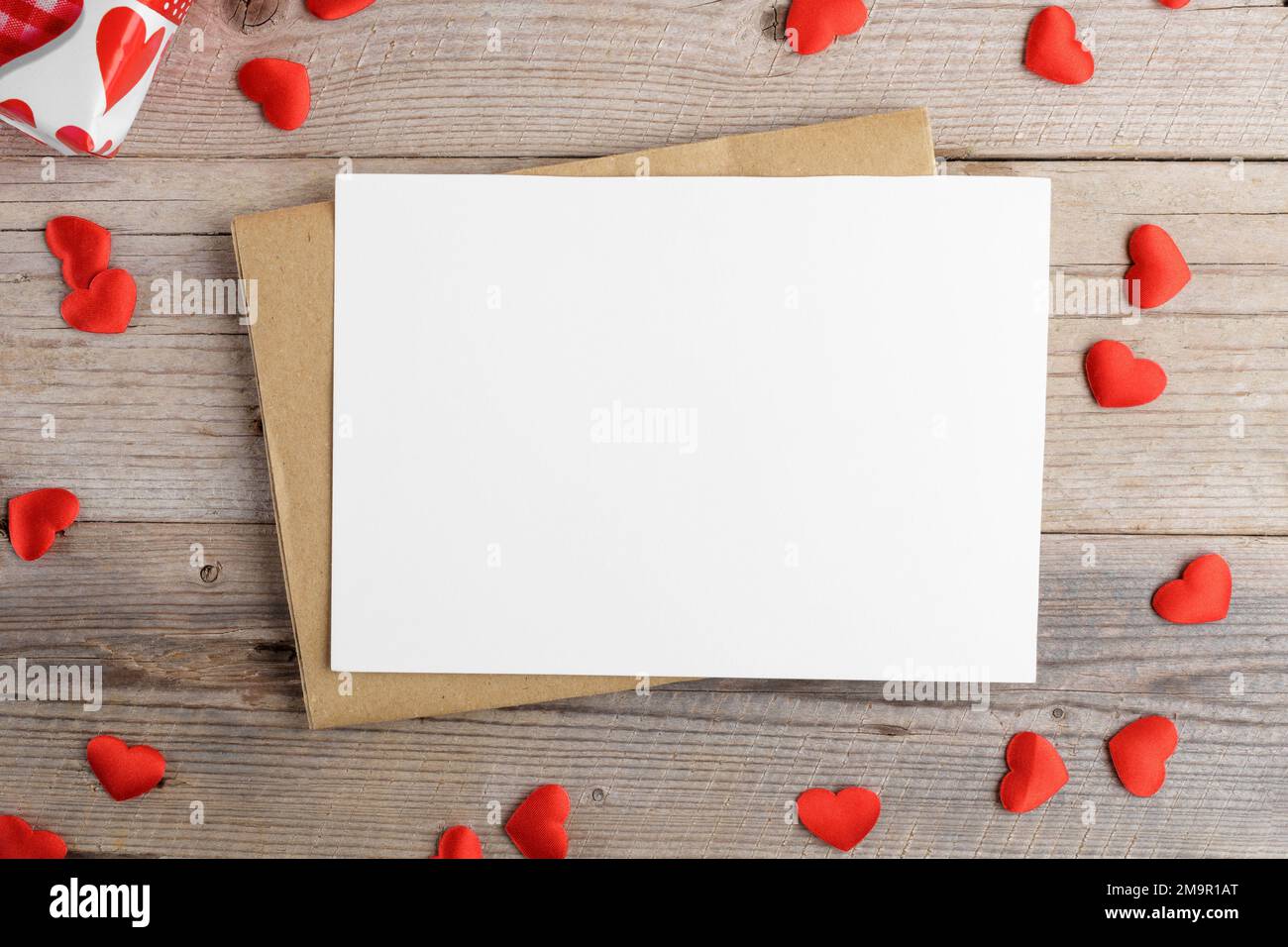 Valentines day card, blank invitation stationery card mockup with envelope and red hearts on wooden background, top view Stock Photo