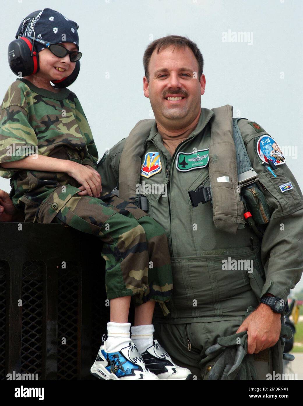 030814-F-2621S-006. [Complete] Scene Caption: Garrett Matuszewski (left) a 10-year-old guest of the Make-A-Wish Foundation, and US Air Force (USAF) Major (MAJ) Michael Digby, an F-16C Fighting Falcon aircraft Pilot, assigned to the 108th Fighter Wing (FW), Ohio National Guard (OHANG), poses for a photograph, on the flight line at Swanton, Ohio. Garrett's wish was to visit a military installation with F-16 fighter aircraft. Members of the 180th FW made sure to make it a memorable trip for Garrett. He spent the day on the flight line watching the jets take off while listening and talking to the Stock Photo