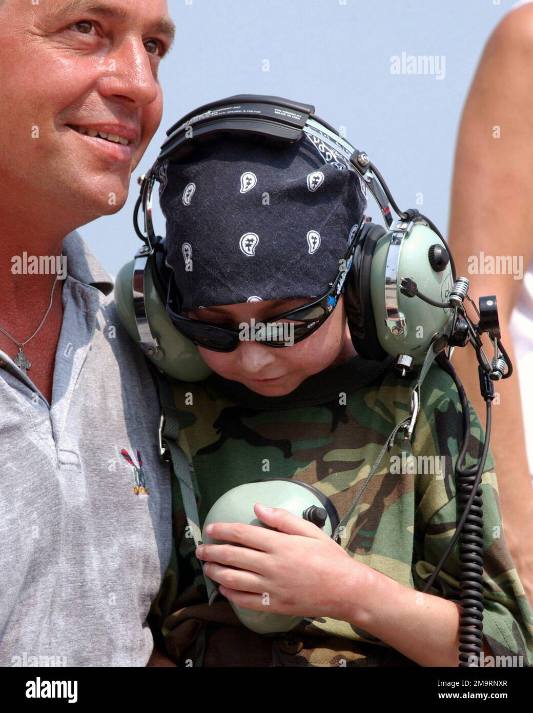 030814-F-2621S-008. [Complete] Scene Caption: Garrett Matuszewski (center) a 10-year-old guest of the Make-A-Wish Foundation talks to pilots on his very own headset, while seated with his father Mr. Mark Matuszewski, during his visit to the 108th Fighter Wing (FW), Ohio National Guard (OHANG), at Swanton, Ohio. Garrett's wish was to visit a military installation with F-16 fighter aircraft. Members of the 180th FW made sure to make it a memorable trip for Garrett. He spent the day on the flight line watching the jets take off while listening and talking to the pilots on his very own headset, le Stock Photo