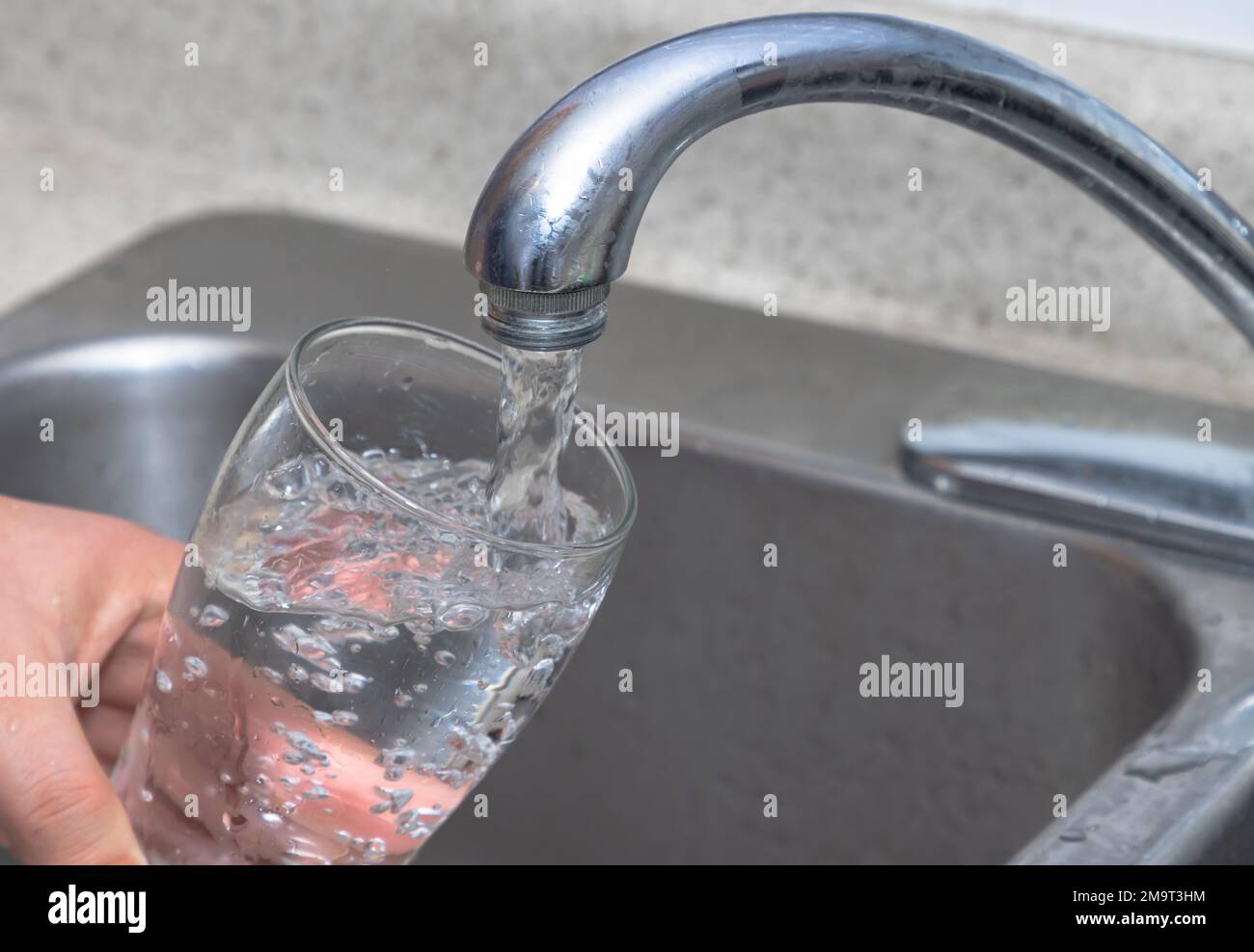 Pouring water into a glass. Filling glass with drinkable water. Stock Photo