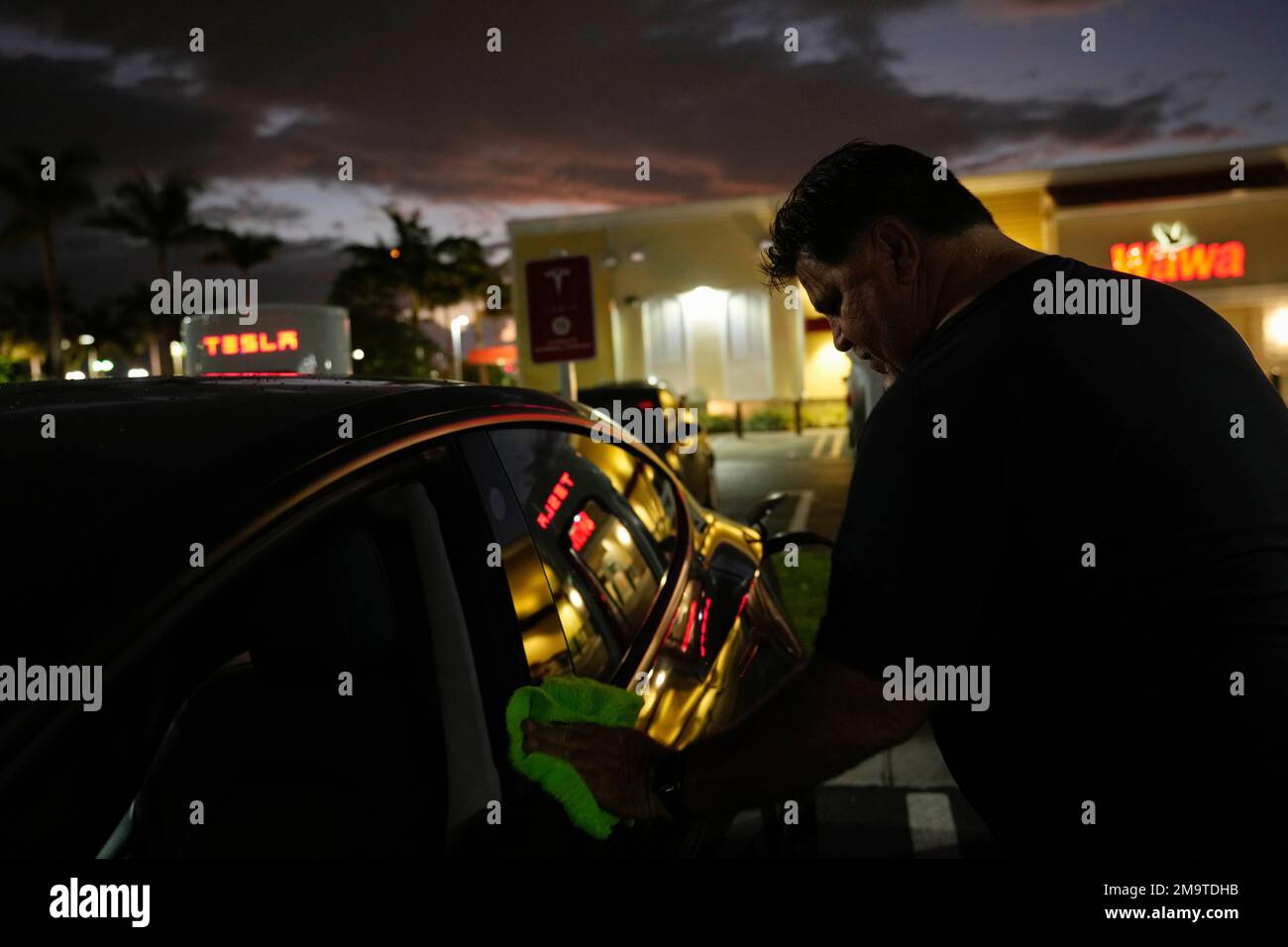 Uber Driver Danny Parson wipes fingerprints of his Tesla as it charges