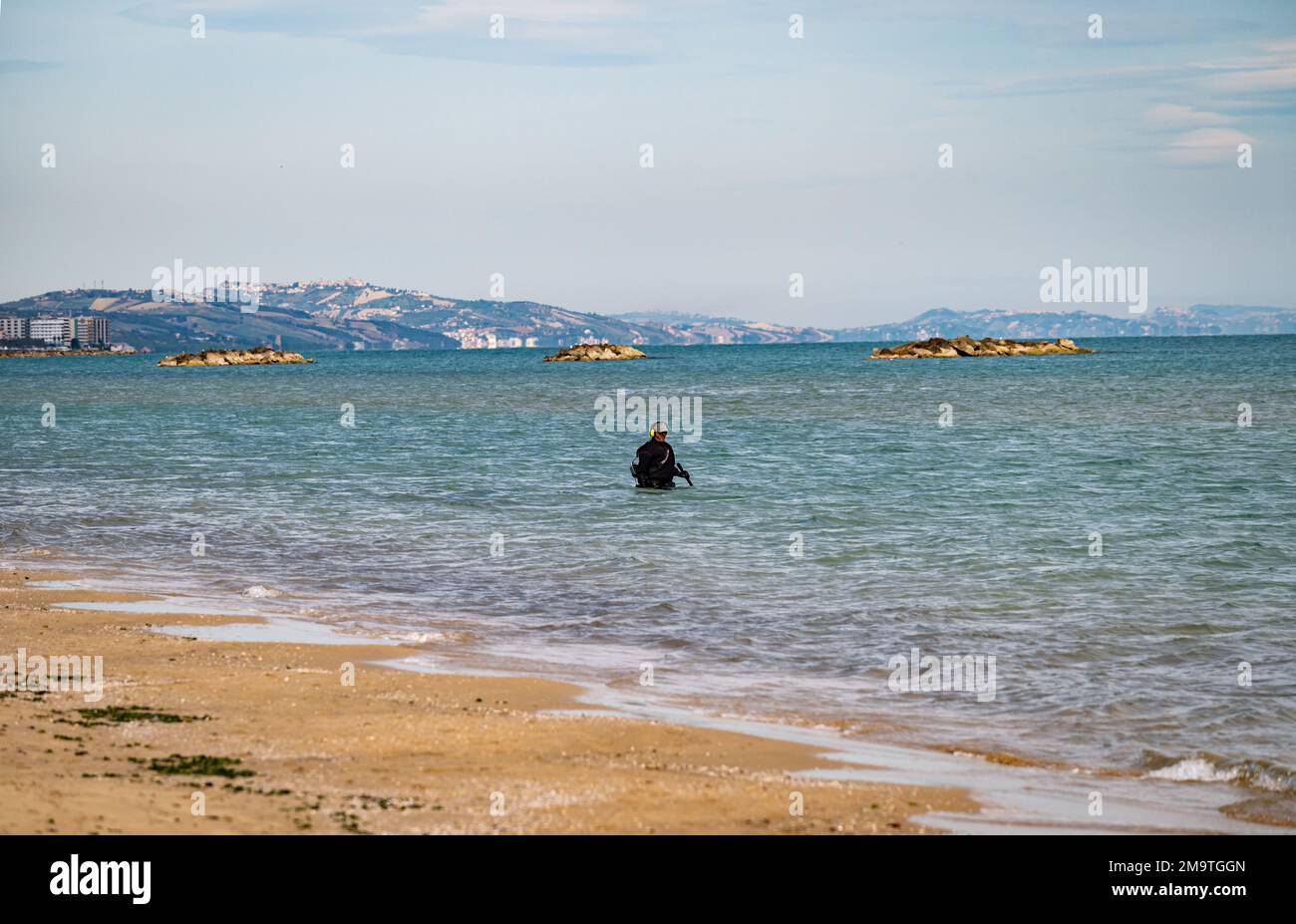 A man in a wetsuit uses underwater metal detector equipment to find valuables in the Adriatic Ocean off the coast of Pescara, Italy. Stock Photo