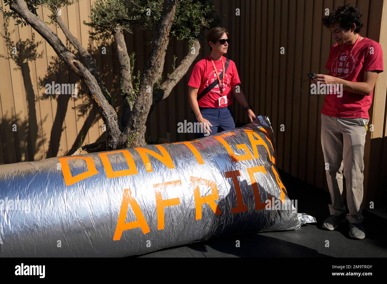Demonstrators stand near a pipeline like object that reads 