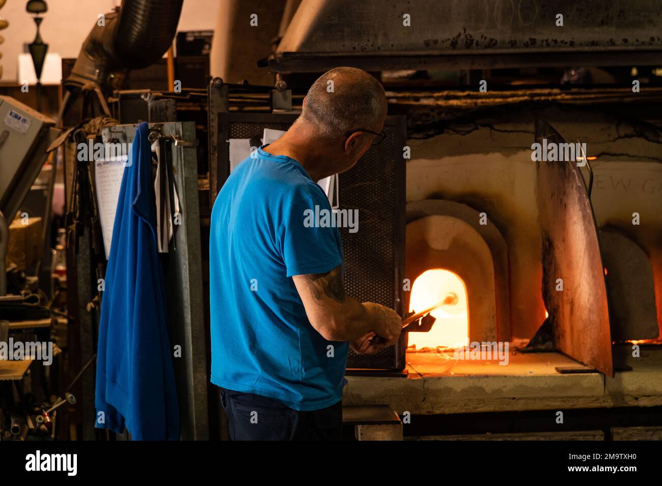 A glassworker holds an orb of glass in one of the ovens at a factor on the island of Murano, in the Venice region of Italy. Stock Photo
