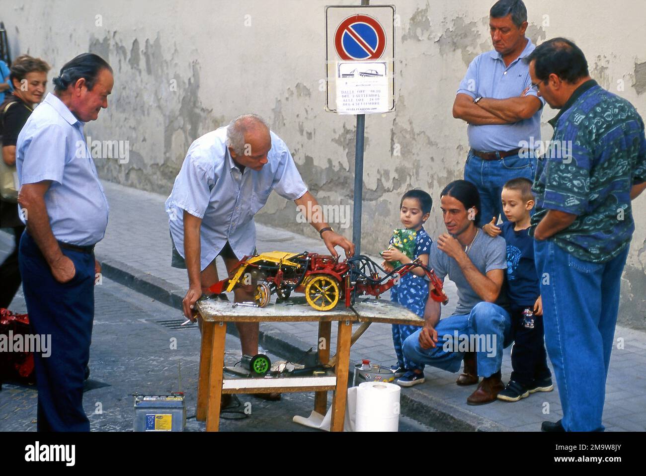 Vendor demonstrating a toy for a man and his children in the streets of Rome, Italy Stock Photo