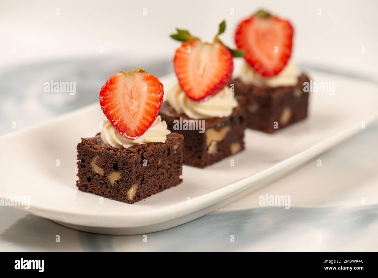 Deliciously rich cake brownie slice with Chantilly cream and fresh strawberry. Stock Photo