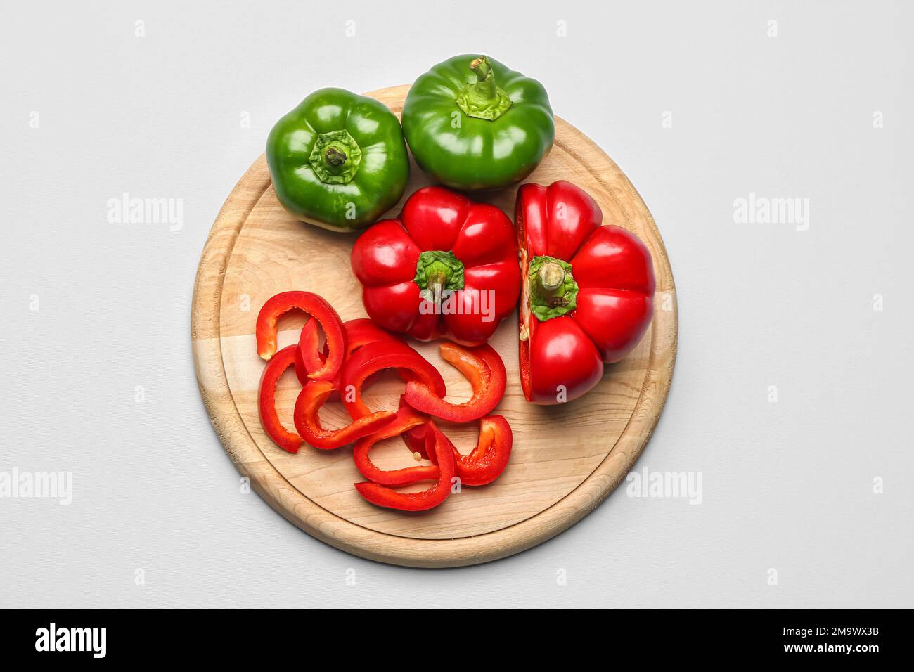 Wooden board with bell peppers on white background Stock Photo - Alamy