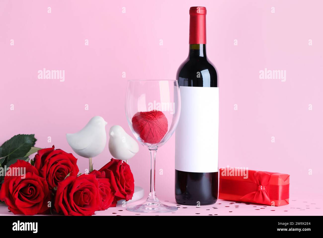 Bottle of wine, glass, rose flowers and heart on pink background ...