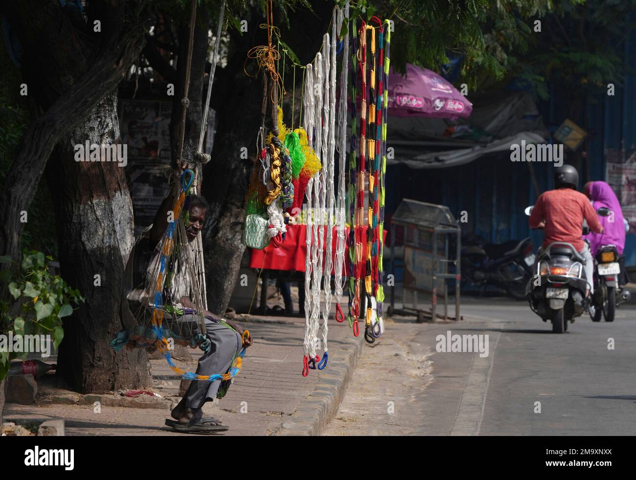 A vendor waits for customer as he sells nylon swings by a roadside in