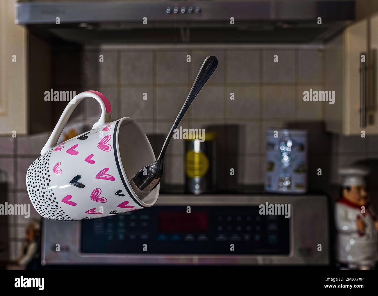 A flying coffee mug with a spoon in the kitchen. Kitchen revolutions and morning dreams. Stock Photo